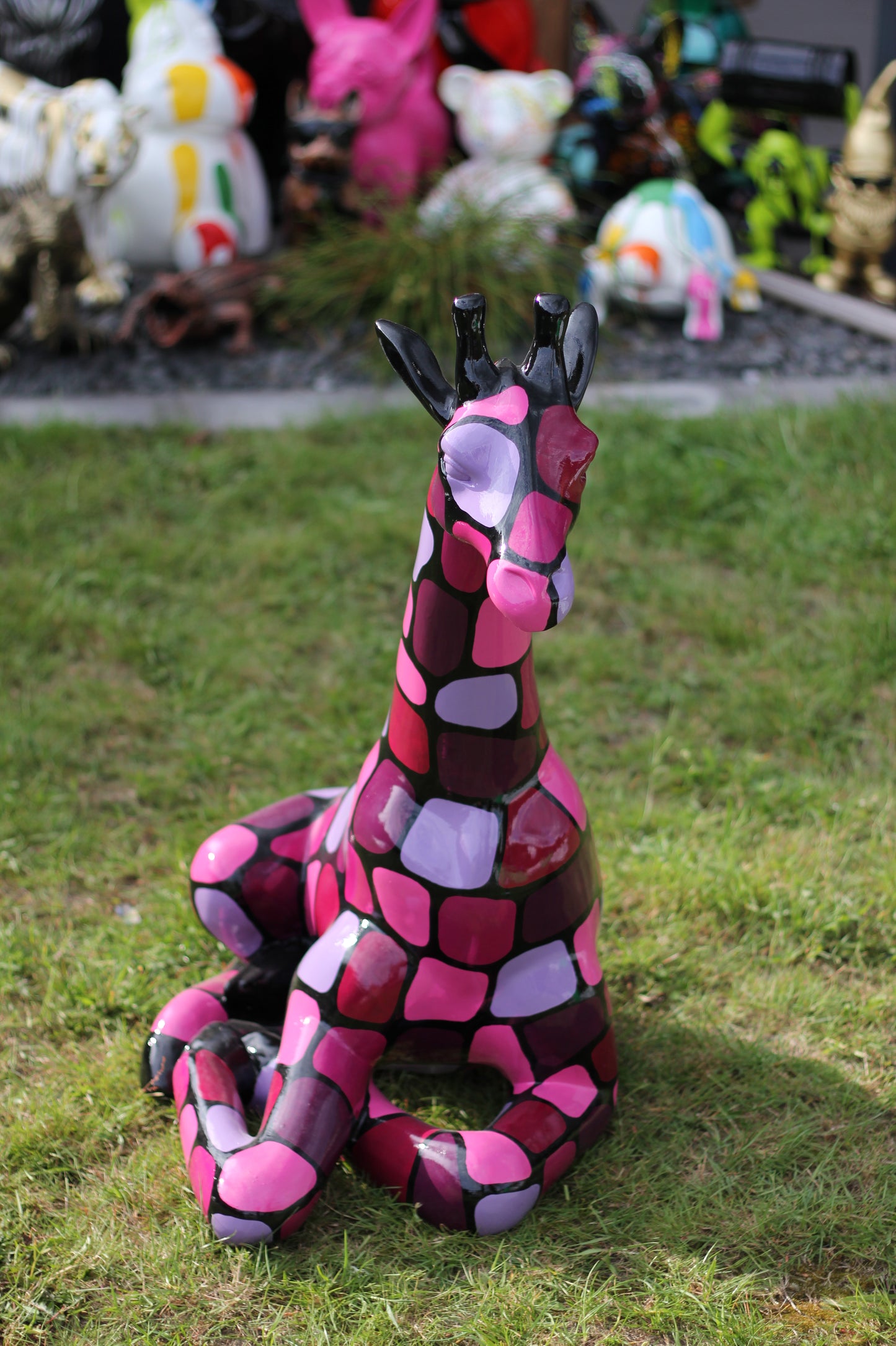 Giraffe sitzend mit lilanen Patches aus Kunstharz - 86cm